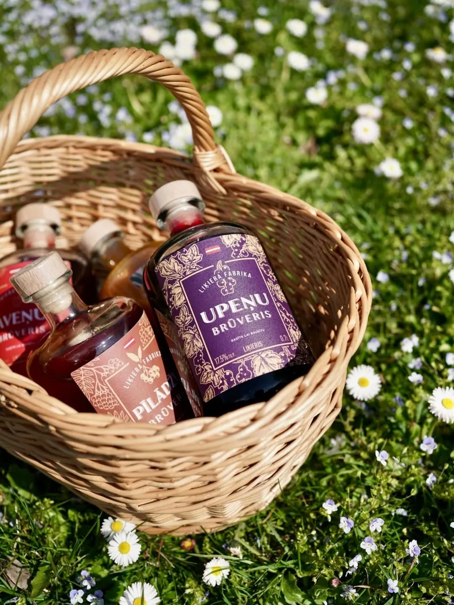 Brūveris bottles in a wicker basket in a flowering meadow